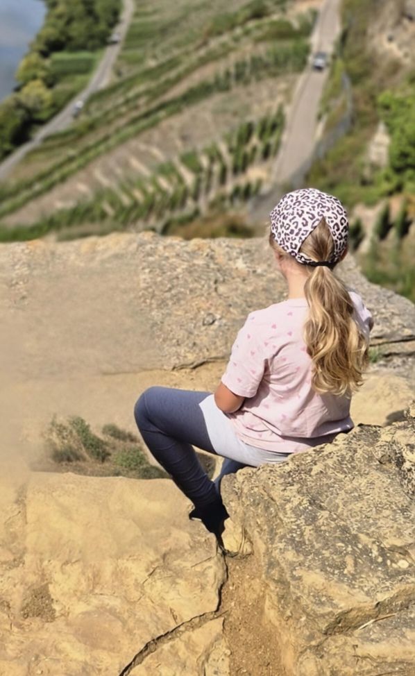 Emily sitzt auf einem Felsen und schaut über die Weinberge
